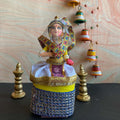 Handcrafted Navaratri Manipuri dancer costume doll in vibrant traditional attire, featuring a headdress and intricate fabric details, standing on a decorative base.