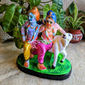Handcrafted Golu doll depicting Krishna and Balram standing with a cow on a grassy base, beautifully painted in vibrant colors.