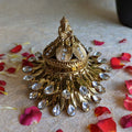 Gold Ganesh kumkum box with intricate detailing, crystal embellishments, and a Ganesha figurine, surrounded by rose petals.