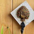 Handcrafted white key holder with a golden peacock motif featuring vibrant green and red accents.