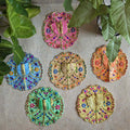 A set of six traditional Lalji Vastras in vibrant colors with intricate embroidery and mirror work, placed on a textured surface with green leaves around.