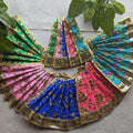 Vibrant and colorful floral Devi skirts with intricate gold embroidery and embellishments, arranged beautifully in a circular pattern.