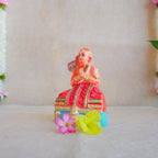 Hand-painted Navarathri Golu doll of Saint Ramanujar in a meditative pose, adorned in vibrant orange and gold attire.