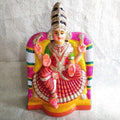 Araikasu Amman Navarathri Golu doll in a red saree and green blouse, seated under a decorative arch with detailed ornaments and vibrant colors.