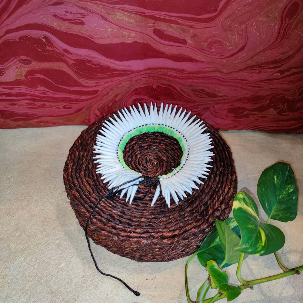 Handcrafted white Konda flower garland with green accents placed on a woven basket, perfect for hair decoration