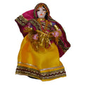Handcrafted Navaratri costume doll of a lady in a pink blouse and yellow skirt, holding a garland, adorned with intricate detailing.