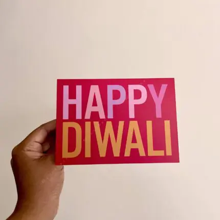 Greeting card that says Happy Diwali on bold pinkish-red background.
