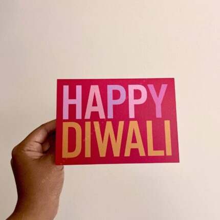 Greeting card that says Happy Diwali on bold pinkish-red background.